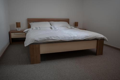 a bed with white sheets and two nightstands with two lamps at Restoran Mijajlovic in Kuršumlija