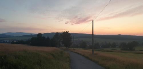 a road in the middle of a field at sunset at Kovářská vyhlídka in Kovářská