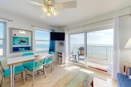 a living room with a table and chairs and a balcony at Tradewinds 601 in Orange Beach