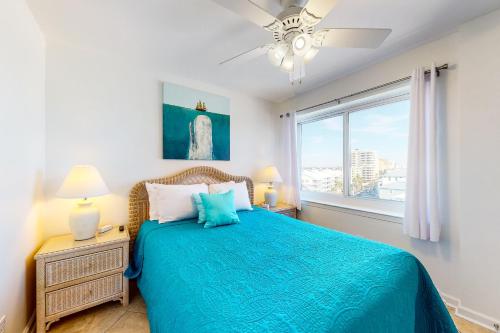 a bedroom with a blue bed and a window at Tradewinds 601 in Orange Beach