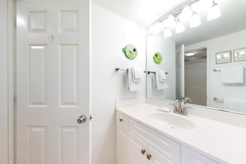 Baño blanco con lavabo y espejo en Tradewinds 601, en Orange Beach