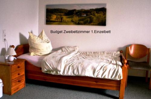 a bed with white sheets and pillows next to a chair at Frankenau Fewo Kellerwald in Frankenau