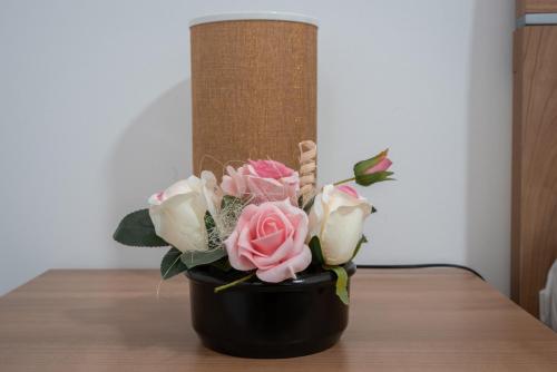 a black vase with pink and white roses on a table at Restoran Mijajlovic in Kuršumlija