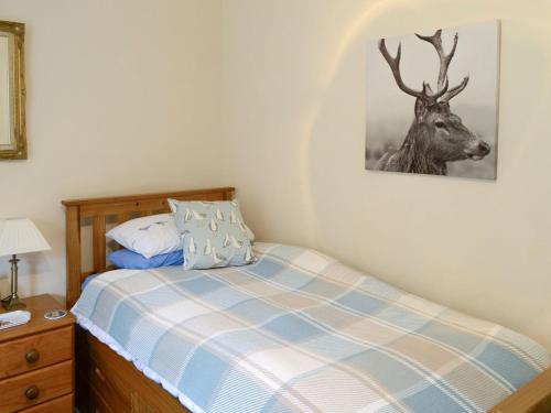 a bedroom with a bed with a deer picture on the wall at Shore Cottage in Rockfield
