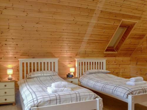 2 letti in una camera con pareti in legno di Quarry Lodge a Little Marcle