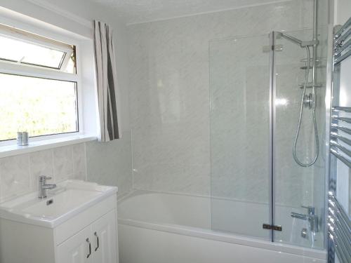 a white bathroom with a shower and a sink at Tregoona in Crantock