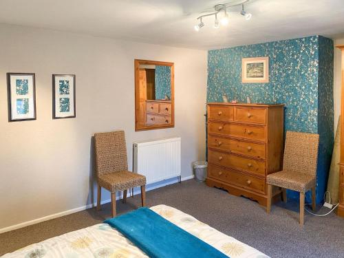 1 dormitorio con 1 cama, 2 sillas y vestidor en Greenpastures en Beaworthy