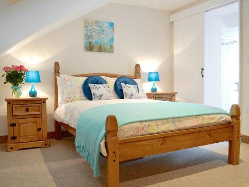 ハートランドにあるTamariskのベッドルーム1室(木製ベッド1台、ブルーランプ、テーブル2台付)