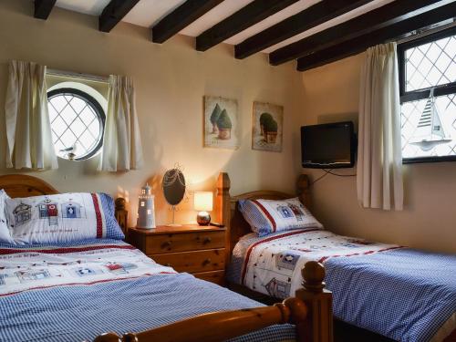 a bedroom with two beds and a tv on the wall at The Studio Cottage in Cemaes Bay