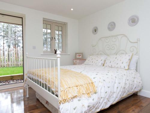a white bedroom with a white bed and a window at Breckland Cottage in Hockwold cum Wilton