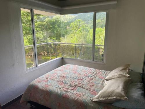 a bedroom with a bed and a large window at Casa del lago garagoa Boyaca in Garagoa