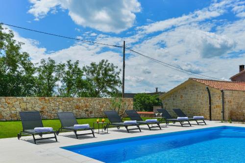 - un groupe de chaises assises à côté de la piscine dans l'établissement Villa Banovi with heated pool, à Knežević