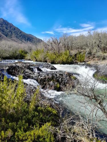 a river in the mountains with snow on the ground at Los Cantos del Agua in Malalcahuello