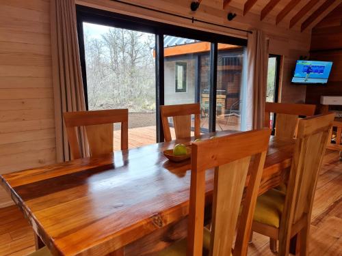 een eetkamer met een houten tafel en stoelen bij Los Cantos del Agua in Curacautín