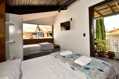 a bedroom with a bed and a balcony with a view at Estúdio com Varanda e Churrasqueira no Campeche P2013 in Florianópolis