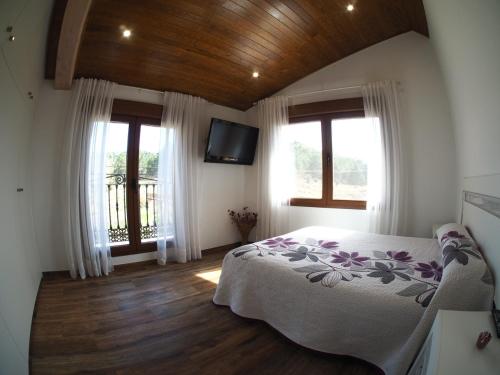 1 dormitorio con 1 cama y 2 ventanas en EL Rincón de Lola, en Carboneras de Guadazaón