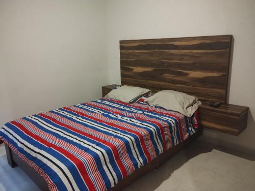a bed with a colorful striped comforter in a room at Torres casillas in Tonalá