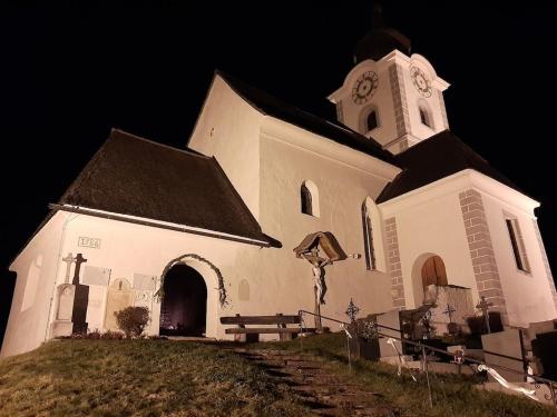 a white church with a clock tower at night at Ferienhaus Kraxlhütte Kärnten in Velden am Wörthersee