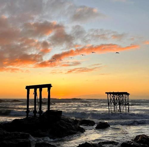 two wooden structures on the beach at sunset at Cabaña de campo in Vichuquén