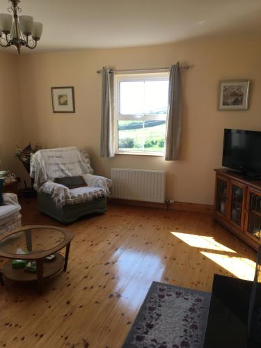 a living room with a couch and a tv at Bungalow by the sea in Gortgarriff