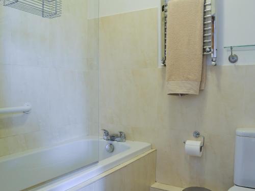 a bathroom with a bath tub and a toilet at Jasmine Cottage in Knitsley