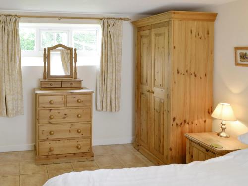 a bedroom with a dresser and a mirror on a dresser at Wren Cottage in Netherbury