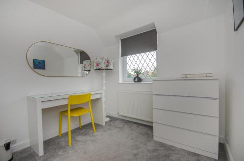 escritorio blanco con espejo y silla amarilla en Hideaway Cottage en Bristol