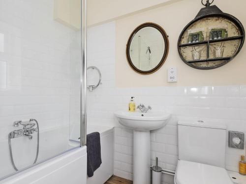 a bathroom with a sink and a toilet and a mirror at Church Cottage in Islip