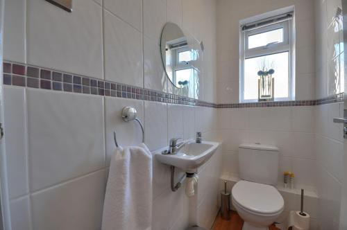 een witte badkamer met een toilet en een wastafel bij Mauve in Poole