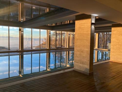a room with large windows and a view of the water at Sunset View Ski & Spa apartments Kopaonik in Kopaonik
