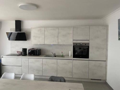 德帕内Appartement la panne Vue laterale sur mer的厨房配有白色橱柜和炉灶烤箱