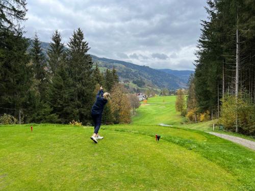 a person jumping in a field with a dog at Alpenferienhaus Kreischberg in Sankt Lorenzen ob Murau