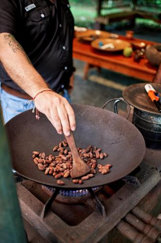 a person cooking food in a pan on a stove at Finca Luna Nueva Lodge in Fortuna