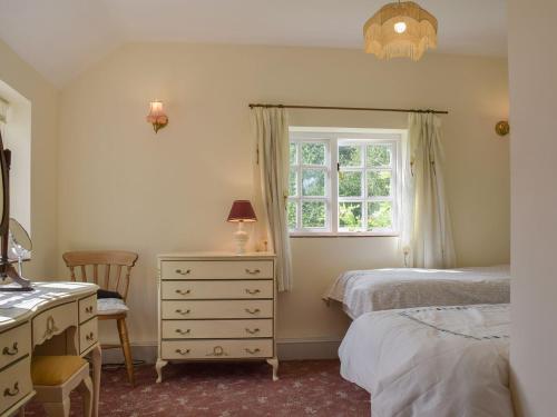 Keepers Cottage Annexe في Edith Weston: غرفة نوم بسريرين وخزانة ونافذة