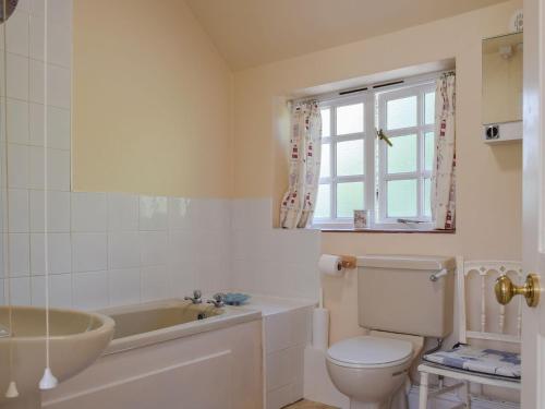 a bathroom with a tub and a toilet and a sink at Keepers Cottage Annexe in Edith Weston