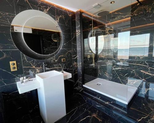 a black marble bathroom with a sink and a mirror at La Suite Luxe : Vue Mer - Malo'cation in Dunkerque
