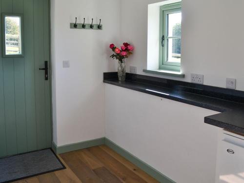 a kitchen with white and green cabinets and a window at East Croft Barn in Halwill