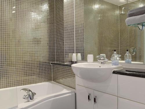 ein weißes Badezimmer mit einem Waschbecken und einem Spiegel in der Unterkunft Gower Sunset Views in Llanelli