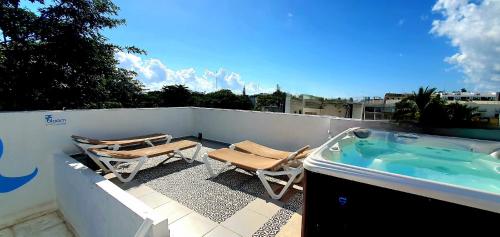 a patio with a hot tub and chairs on a balcony at Bloom! exclusive boutique b&b in Playa del Carmen