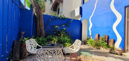 two chairs and a table in front of a blue wall at Bloom! exclusive boutique b&b in Playa del Carmen