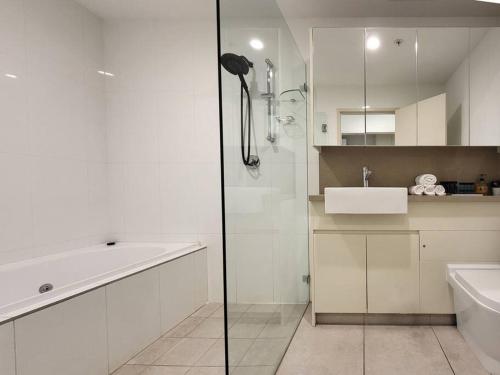 a bathroom with a shower and a sink and a bath tub at Spacious 3-Bed Penthouse with Perfect View in Sydney