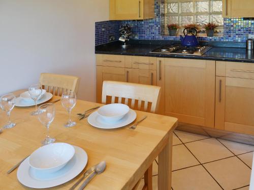 a kitchen with a wooden table with plates and wine glasses at Beachcomber in Mundesley