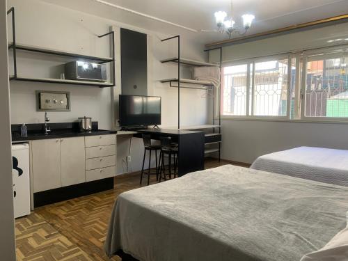 a bedroom with two beds and a kitchen with a desk at Pousada Hostel Dodora in Bento Gonçalves