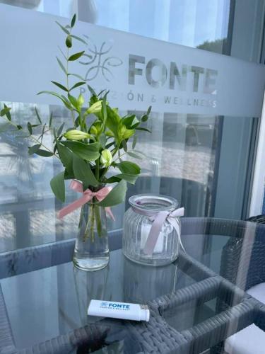 a glass table with a vase of flowers on it at Penzión Fonte in Radava