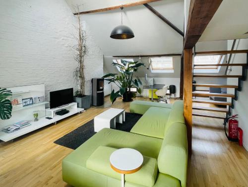 a living room with a green couch and a tv at Spacious Loft in the Historical Centre in Ghent