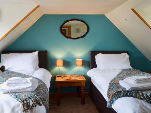 a attic room with two beds and a mirror at West End Cottage in Carrbridge