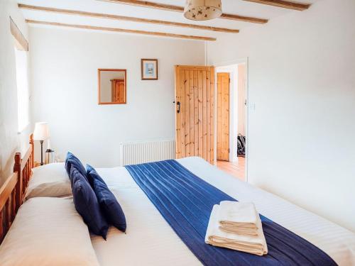 een witte slaapkamer met een groot bed met blauwe kussens bij The Parlour - Uk6717 in Lydstep