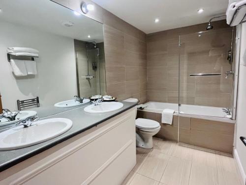 a bathroom with two sinks and a toilet and a shower at The Blue Piano Guesthouse in Birmingham