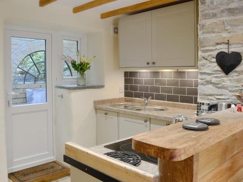 une cuisine avec des placards blancs et un comptoir dans l'établissement Annies Cottage, à Buckland Monachorum