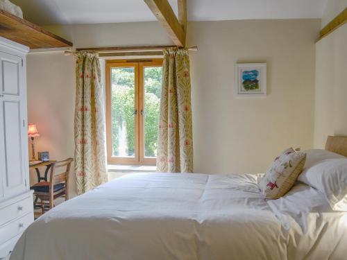 a bedroom with a white bed and a window at Annies Cottage in Buckland Monachorum